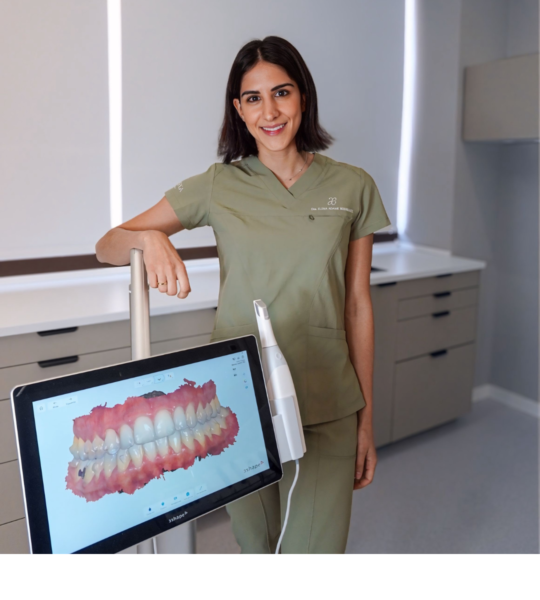 Odontóloga de la Clínica Adame & Espiga en Rivas Vaciamadrid explicando el plan de tratamiento de ortodoncia invisible a una paciente adulta frente a una radiografía dental panorámica digital en un monitor.